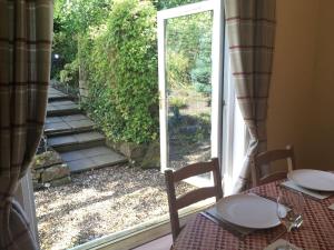 a room with a table and a sliding glass door at Herb Wood Cottage in Hawick