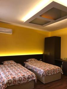 two beds in a room with yellow walls at Център in Pleven