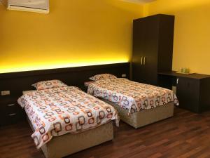 2 łóżka w pokoju z żółtymi ścianami w obiekcie Център w mieście Plewen