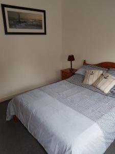 a bedroom with a blue and white bed with a picture on the wall at Marina Apartment in La Forêt-Fouesnant