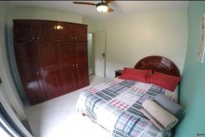 a bedroom with a bed with red pillows on it at Apartamento Residencial Angélica em Guarapari a 150m do mar in Guarapari