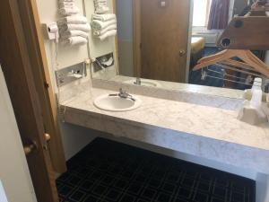 eine Badezimmertheke mit einem Waschbecken und einem Spiegel in der Unterkunft Sunset Inn and Suites in Seward