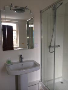ein Bad mit einem Waschbecken und einer Dusche mit einem Spiegel in der Unterkunft The Masons Arms Hotel in Bridgend