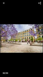 duży budynek z fioletowymi kwitnącymi drzewami przed nim w obiekcie Stylish Apartment in the heart of Málaga with Pool w Maladze