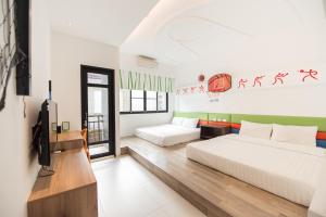 a bedroom with two beds and a flat screen tv at Her Man Hostel in Xiaoliuqiu