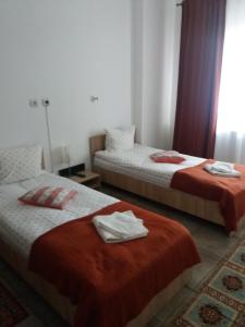 um quarto com 2 camas com lençóis vermelhos e brancos em Cazare NEU-ARAD AUTOSTRADA em Arad