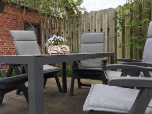 a table and chairs on a patio next to a fence at Ferienhaus Janik in Friedrichskoog