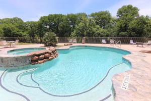 a swimming pool with a rock wall around it at Rose' River Retreat in New Braunfels