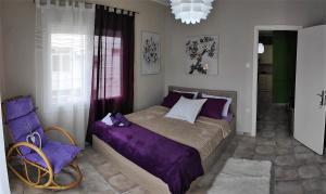 1 dormitorio con 1 cama de color púrpura y 1 silla en Cozy apartments, en Komotiní