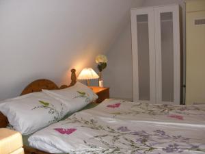 a bedroom with two beds and a lamp and flowers at Ferienwohnung Roman in Tinnum