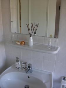 a bathroom with a white sink and a mirror at Ferienwohnung Roman in Tinnum +4 photos
