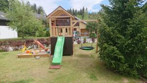 une maison avec une aire de jeux dans la cour dans l'établissement Villa Park Lipno 206, à Lipno nad Vltavou