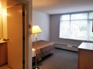 a small bedroom with a bed and a window at Carey Centre in Vancouver