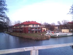 a boat is docked next to a house on a river at APARTAMENT JULIA in Ostróda
