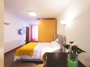 um quarto de hotel com uma cama com um cobertor amarelo em Flat 1 at 6 Taunton Mews em Londres