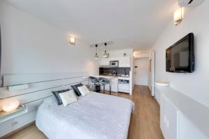 a white bedroom with a bed and a television at Studio la Plage in Roquebrune-Cap-Martin