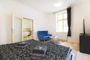 a bedroom with a bed and a blue chair at Pilsner Apartments - U Matky Boží in Pilsen