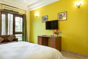 a bedroom with a bed and a tv on a yellow wall at Hostie - 4BHK Apartment with lift near Greater Kailash, South Delhi in New Delhi