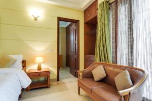 a bedroom with a couch and a bed and a mirror at Hostie - 4BHK Apartment with lift near Greater Kailash, South Delhi in New Delhi