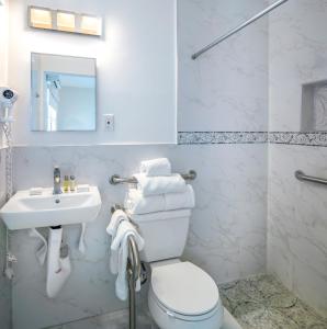 bagno bianco con servizi igienici e lavandino di St. Pete Beach Suites a St Pete Beach