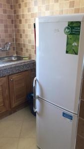 La cuisine est équipée d'un réfrigérateur blanc et d'un évier. dans l'établissement Oum Khaltoum Martil, à Martil