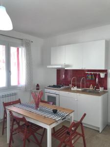 uma cozinha com mesa e cadeiras e uma cozinha com armários brancos em Little house em Mazara del Vallo