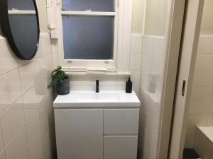 La salle de bains est pourvue d'un lavabo blanc et d'une fenêtre. dans l'établissement Central Club Hotel, à Melbourne