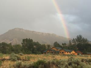a rainbow over a house in a field at The Remington Cabin in Wapiti