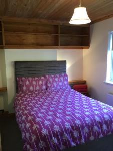 Cama en habitación con colcha púrpura en St Judes House, en Killarney