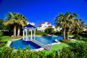 a swimming pool with a gazebo and palm trees at 38 Fantastic Holiday // AC - WIFI in La Mata