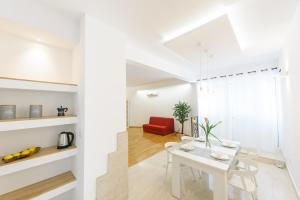 een witte woonkamer met een witte tafel en een rode stoel bij Deluxe Beach Apartments Renata in Split