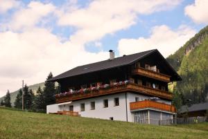 Una casa en una colina con flores. en Ferienwohnungen Niederarnigerhof Familie Bauernfeind, en Kals am Großglockner