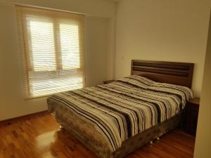 1 dormitorio con 1 cama con edredón a rayas y ventana en Jirón Tarapacá 398, La Punta - Callao, en Lima