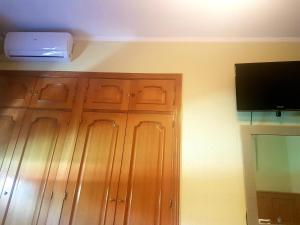 ブルネテにあるオスタル ブルネテの木製のキャビネットと壁掛けテレビが備わる客室です。