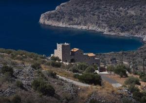 un edificio su una collina vicino a un corpo d'acqua di Focalion Castle Luxury Suites a Pyrgos Dirou