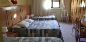 ブルネテにあるオスタル ブルネテのベッド3台、テーブル、椅子が備わる客室です。