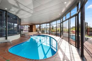 uma piscina interior num edifício com janelas de vidro em Mantra Bathurst em Bathurst