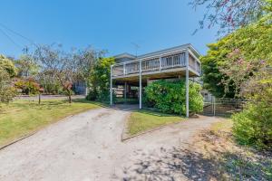 a house with a wrap around porch on a dirt road at INVERLOCH BEACH HUT - CLOSE TO BEACH AND SHOPS! in Inverloch