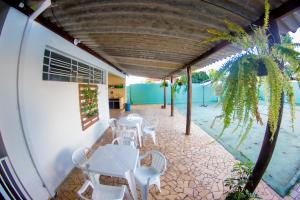 a patio with white tables and chairs and a palm tree at Hostel Bauru in Bauru