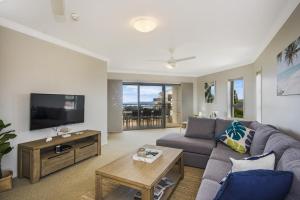 a living room with a couch and a tv at Breakers 2 12 - LJHooker Yamba in Yamba