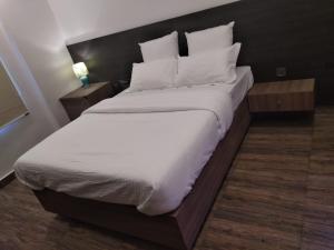 a bedroom with a large bed with white sheets and pillows at Samsan Residentia in Visakhapatnam