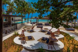 an outdoor patio with chairs and tables and the ocean at Lotus Beach Hotel - Adults Only in Isla Mujeres