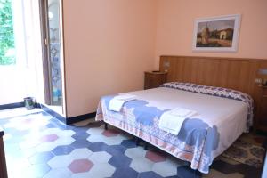 a bedroom with a bed and a tiled floor at Albergo Belvedere in Acqui Terme