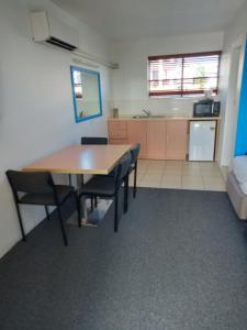 a kitchen with a table, chairs and a refrigerator at Annerley Motor Inn in Brisbane
