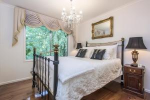 a bedroom with a bed and a chandelier at The Beeches - Olinda in Olinda