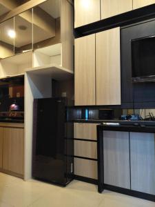 una cocina con electrodomésticos negros y armarios de madera en Capitol Park Minimum Stay 2 Nights en Yakarta