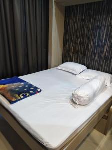 Una cama con una almohada y un libro encima. en Capitol Park Minimum Stay 2 Nights, en Yakarta