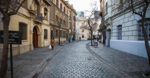a woman walking down a cobblestone street with buildings at Hotel Plaza Londres 77 in Santiago