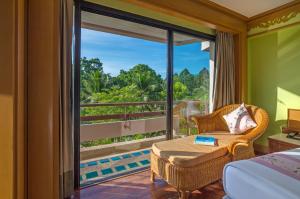 a room with a bed and a table and a window at Maritime Park And Spa Resort in Krabi town