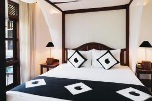 um quarto com uma cama com almofadas pretas e brancas em Amal Beach Hotel em Bentota